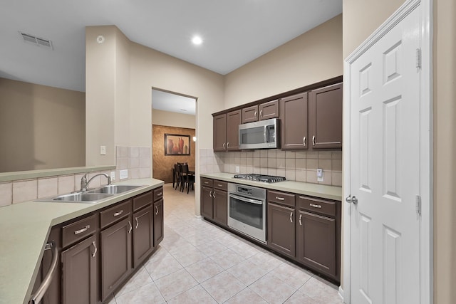 kitchen with dark brown cabinetry, light tile patterned flooring, light countertops, a sink, and appliances with stainless steel finishes