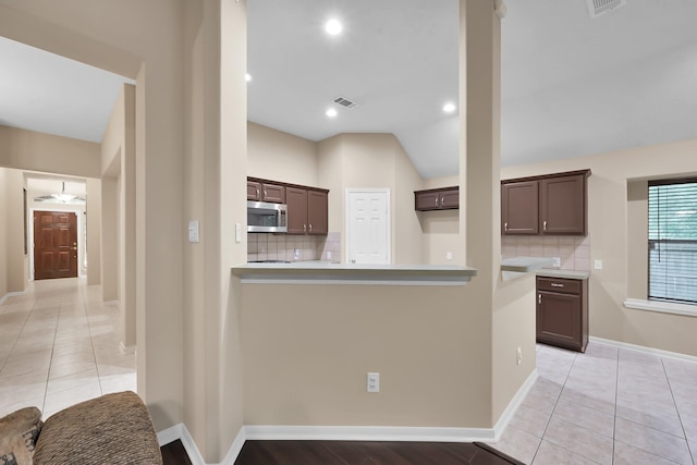 kitchen featuring visible vents, decorative backsplash, dark brown cabinets, light countertops, and stainless steel microwave