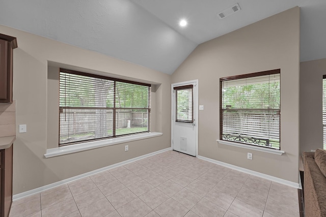 unfurnished room with light tile patterned floors, baseboards, lofted ceiling, and visible vents