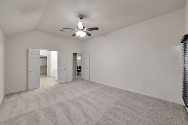 unfurnished bedroom with a walk in closet, light colored carpet, visible vents, vaulted ceiling, and baseboards