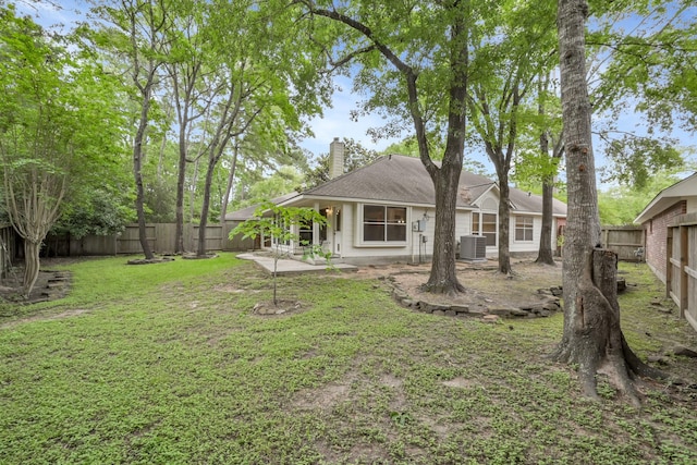 back of house with a chimney, a lawn, a patio area, cooling unit, and a fenced backyard