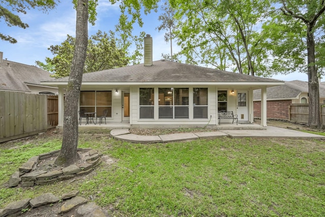 rear view of property featuring a yard, a chimney, a fenced backyard, and a patio area