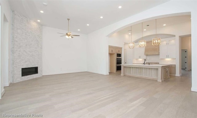 unfurnished living room featuring recessed lighting, a ceiling fan, light wood finished floors, and a stone fireplace