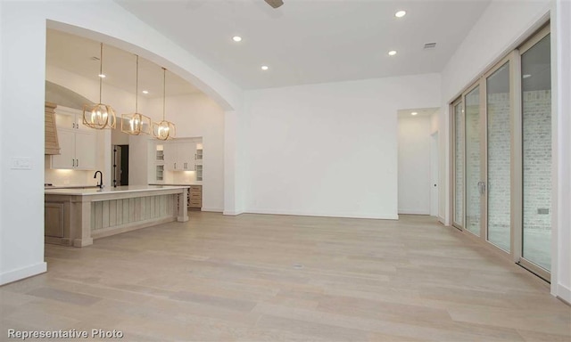 interior space with recessed lighting, baseboards, arched walkways, and light wood-style floors