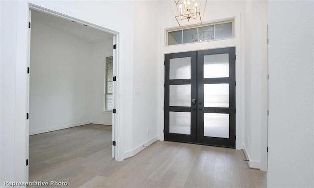 entrance foyer with baseboards, a notable chandelier, french doors, and light wood-style floors
