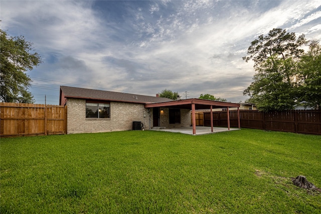 back of property with brick siding, a fenced backyard, a patio area, and a yard