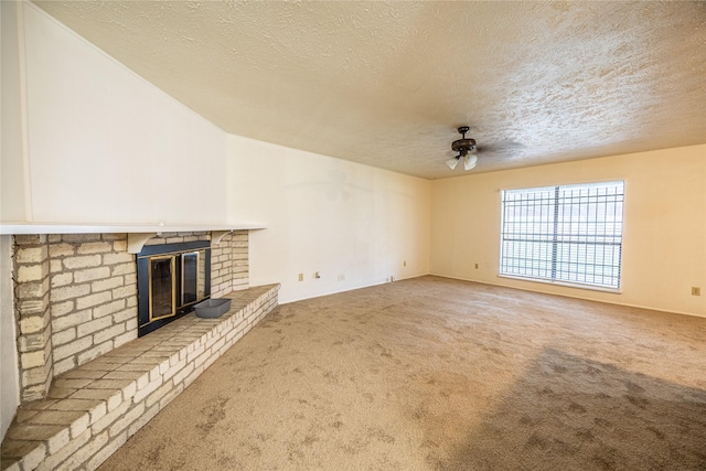 unfurnished living room with carpet, a ceiling fan, a textured ceiling, and a brick fireplace