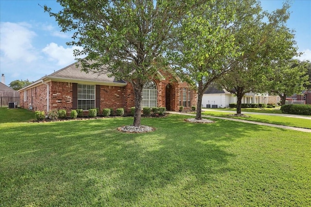 view of front facade with central AC unit, a front yard, and brick siding