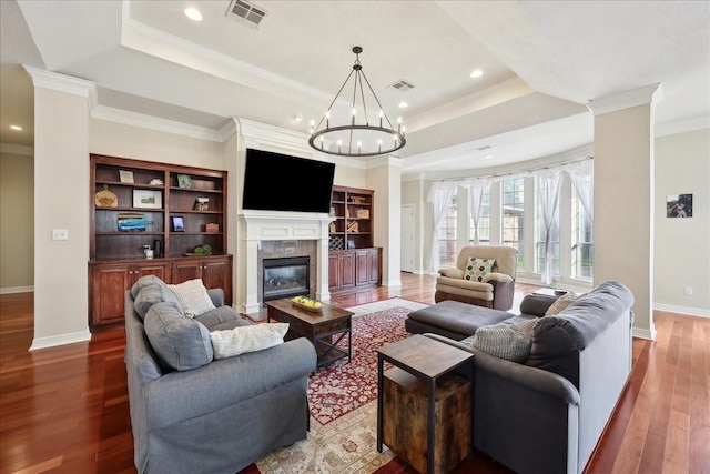living area featuring visible vents, baseboards, dark wood-style flooring, and a tray ceiling