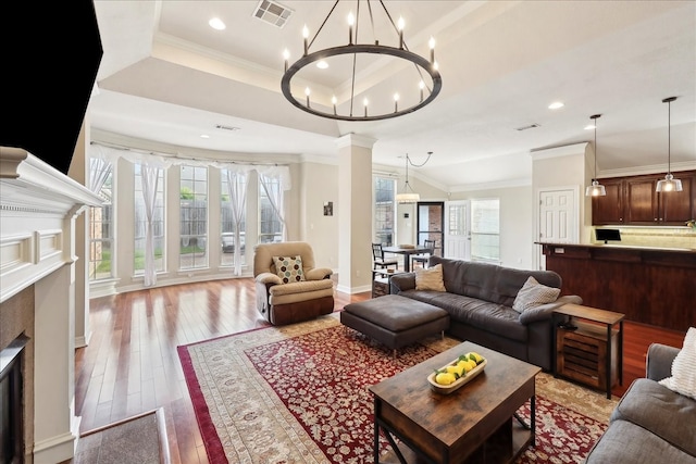 living room with visible vents, ornamental molding, light wood-style floors, a high end fireplace, and a notable chandelier