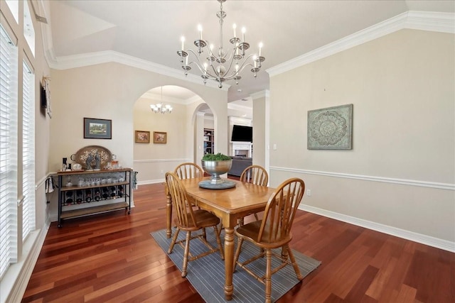 dining room with crown molding, arched walkways, wood finished floors, baseboards, and a notable chandelier