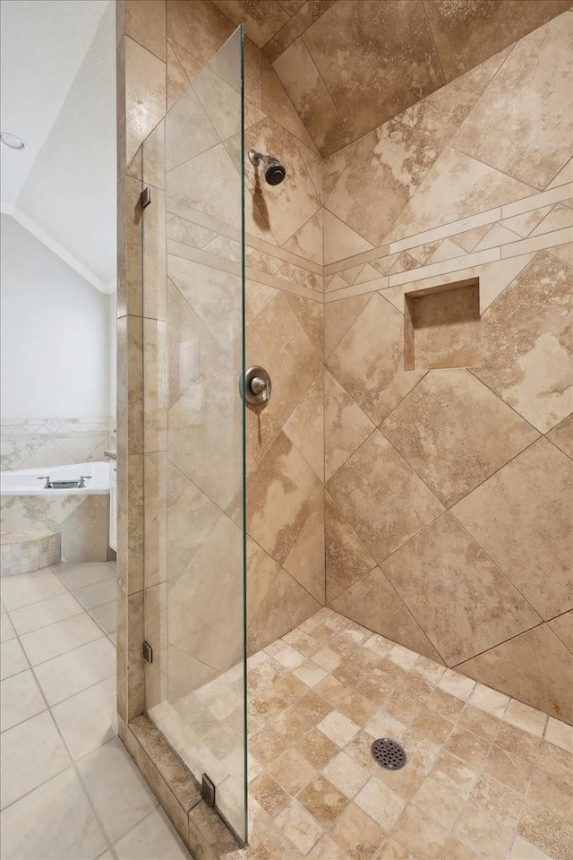 bathroom featuring crown molding, tile patterned flooring, lofted ceiling, a bathing tub, and a tile shower