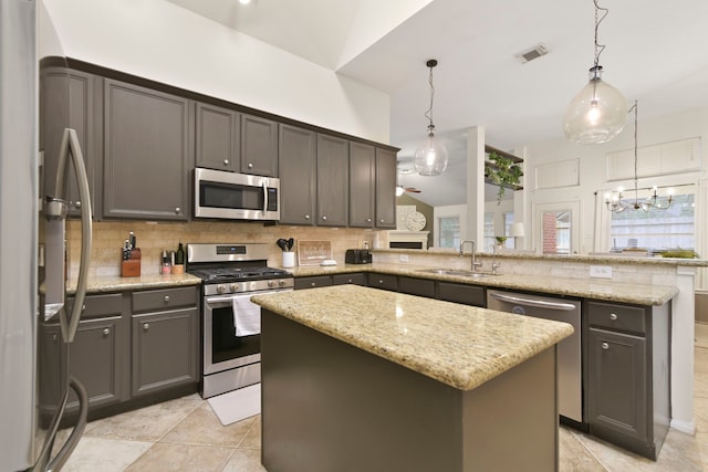 kitchen with appliances with stainless steel finishes, a sink, a peninsula, decorative backsplash, and visible vents