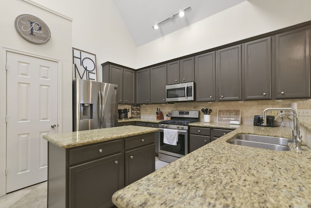 kitchen with a sink, decorative backsplash, light stone countertops, and stainless steel appliances