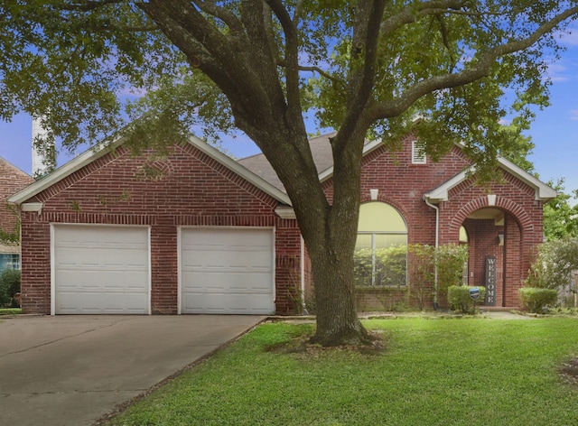 traditional-style home featuring an attached garage, concrete driveway, a front lawn, and brick siding