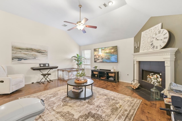 living room with ceiling fan, visible vents, a tiled fireplace, wood finished floors, and vaulted ceiling