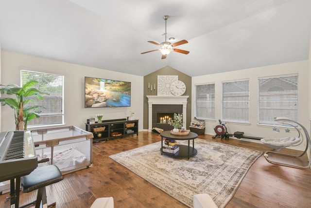 living room with ceiling fan, a tiled fireplace, wood finished floors, and lofted ceiling