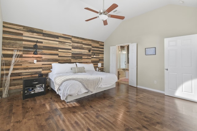 bedroom with connected bathroom, high vaulted ceiling, wood walls, baseboards, and wood finished floors