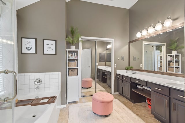 bathroom with double vanity, tile patterned flooring, a garden tub, and a sink