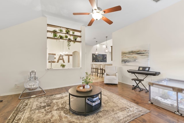 living area with visible vents, ceiling fan, wood finished floors, and vaulted ceiling