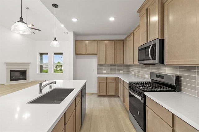 kitchen featuring a ceiling fan, backsplash, a sink, light wood-style floors, and stainless steel appliances