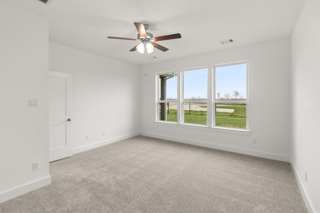 carpeted empty room featuring baseboards, a ceiling fan, and visible vents