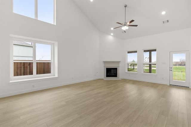 unfurnished living room featuring ceiling fan, visible vents, high vaulted ceiling, baseboards, and a glass covered fireplace
