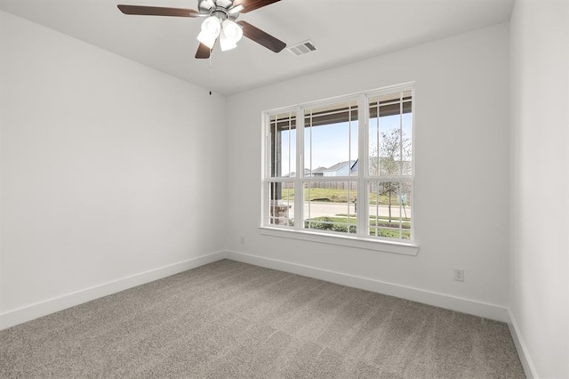 carpeted empty room featuring baseboards, visible vents, and ceiling fan