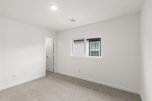spare room with carpet flooring, baseboards, and visible vents