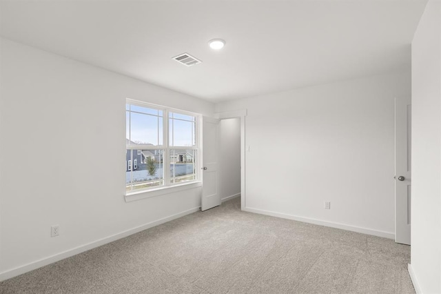 empty room featuring carpet floors, baseboards, and visible vents