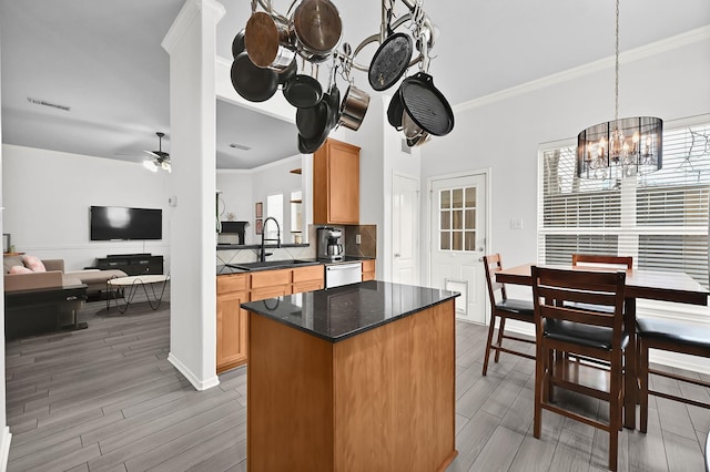 kitchen with crown molding, a sink, dishwasher, ceiling fan with notable chandelier, and visible vents