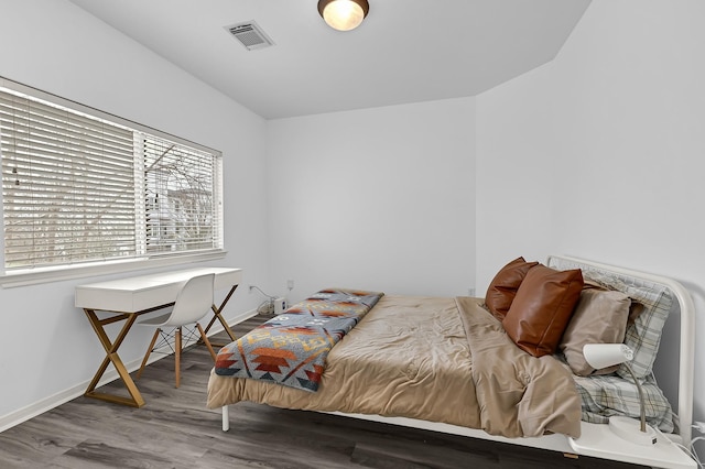 bedroom with visible vents, baseboards, and wood finished floors