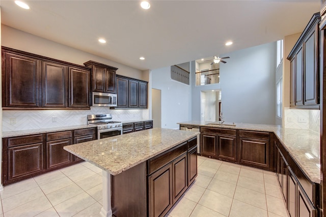 kitchen with light tile patterned floors, backsplash, stainless steel appliances, and a center island
