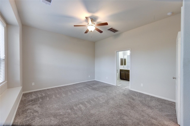 carpeted spare room with visible vents, baseboards, and ceiling fan