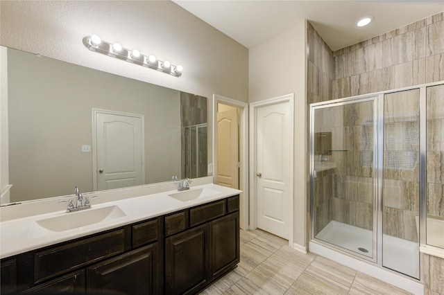 bathroom featuring a sink, double vanity, a shower stall, and tile patterned floors