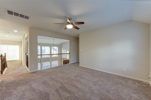 carpeted empty room with visible vents, baseboards, and a ceiling fan