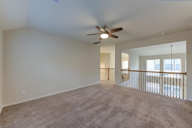 carpeted empty room featuring ceiling fan, lofted ceiling, baseboards, and visible vents