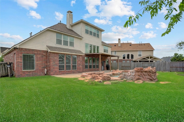 rear view of property with a lawn, brick siding, a chimney, and a fenced backyard