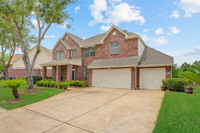 view of front of home featuring a shingled roof, a front yard, driveway, and brick siding
