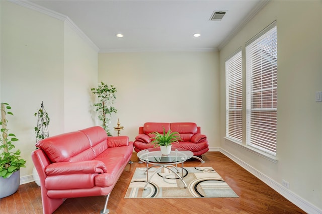 living area with crown molding, baseboards, visible vents, and wood finished floors