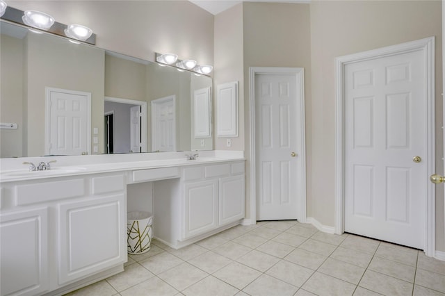 full bath with a sink, tile patterned floors, baseboards, and double vanity