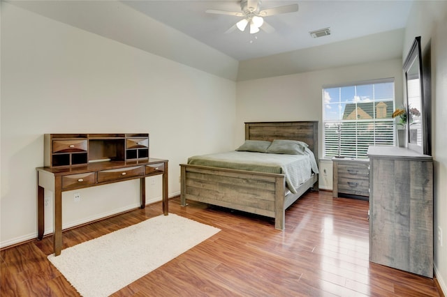 bedroom with a ceiling fan, baseboards, visible vents, and wood finished floors