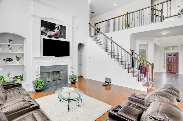 10007 Autumn Lake Trl, Pearland, TX 77584 - living room featuring a high ceiling, stairway, a fireplace, wood finished floors, and baseboards