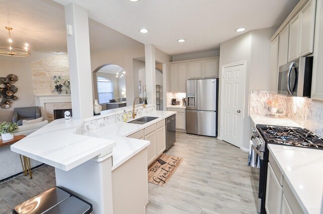 15027 Wildberry Creek Ct, Cypress, TX 77433 - kitchen featuring arched walkways, tasteful backsplash, a sink, light wood-style floors, and stainless steel appliances