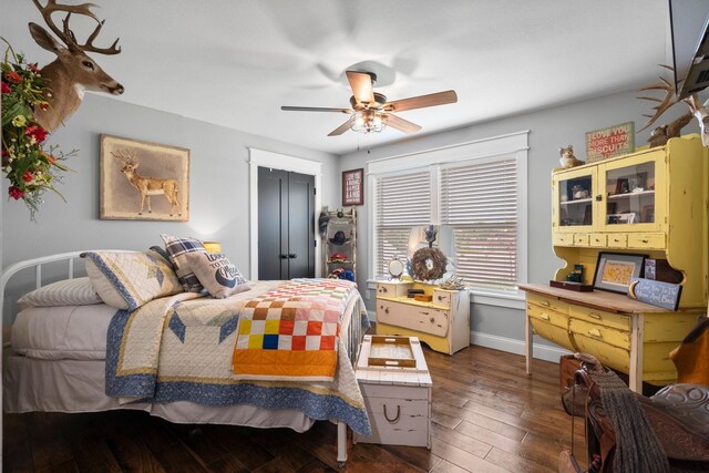 bedroom featuring baseboards, dark wood finished floors, ceiling fan, and a closet