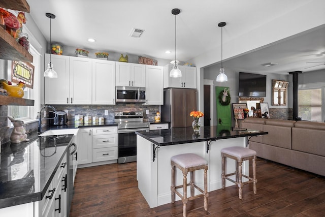 kitchen featuring appliances with stainless steel finishes, a sink, dark wood finished floors, open floor plan, and tasteful backsplash