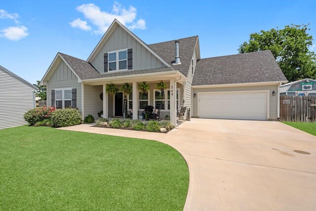 craftsman-style home featuring a front lawn, fence, a shingled roof, board and batten siding, and driveway
