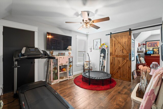 exercise room with wood finished floors, baseboards, ceiling fan, a barn door, and vaulted ceiling