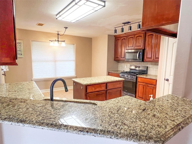 110 Hummingbird Ct, Richwood, TX 77566 - kitchen featuring decorative backsplash, appliances with stainless steel finishes, rail lighting, a sink, and light stone counters