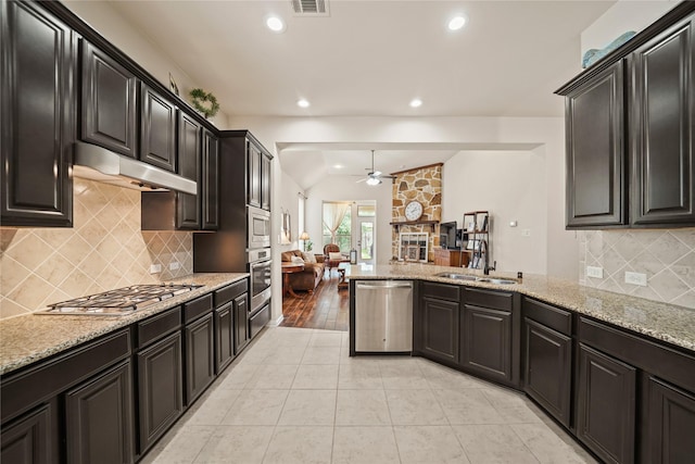 21023 Barrett Woods Dr, Richmond, TX 77407 - kitchen with a stone fireplace, ceiling fan, under cabinet range hood, a sink, and stainless steel appliances